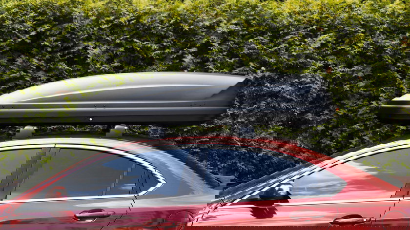 coffre-installe-sur-le-toit-d-une-berline-rouge-equipement-pour-les-voyages-concept-de-transport-de-stockage